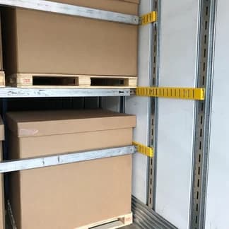 Two Exact-A-Track brackets and horizontal load bars shown across palletized freight