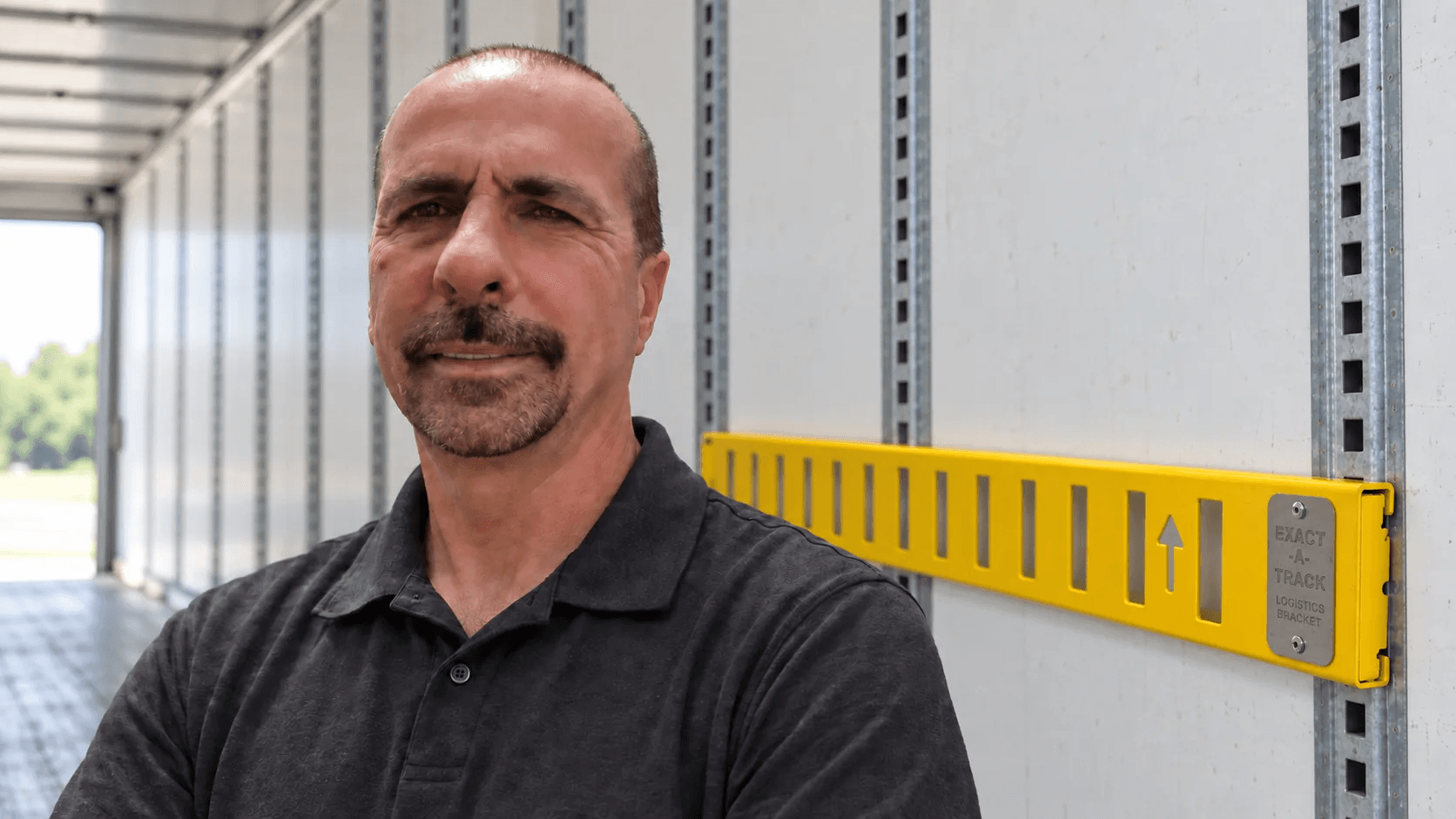 Richard Meyers beside the Exact-A-Track logistics bracket inside a freight trailer